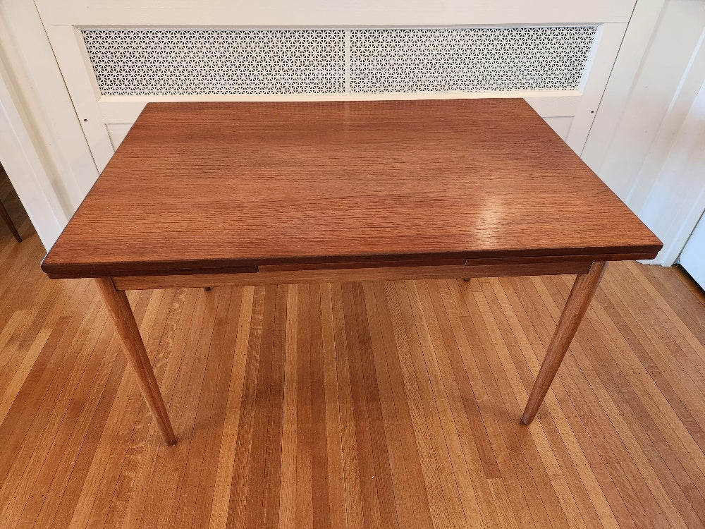 Perfect size Danish extending teak dining table for a smaller space. At only 48"L, the table can extend up to 79"L with the two hidden leaves. Classic design with continuous grain and tapered legs. Made in Denmark by Farstrup- Cook Street Vintage