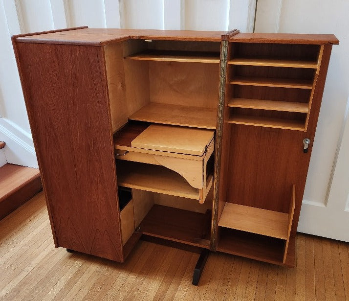 multifunctional teak folding desk designed by Swiss architects Ernst Mummenthaler and Otto Meier to resemble a cabinet. This midcentury piece opens to reveal numerous adjustable shelves and a drawer that pulls out to create the perfect work surface for your laptop or for writing. A retractable reading lamp automatically turn son when you pull it out.&nbsp; &nbsp;Recently restored, it comes with a set of keys to lock the unit once closed.- Cook Street Vintage