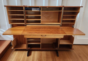 Magic Box Desk multifunctional teak folding desk designed by Swiss architects Ernst Mummenthaler and Otto Meier to resemble a cabinet. This midcentury piece opens to reveal numerous adjustable shelves and a drawer that pulls out to create the perfect work surface for your laptop or for writing. A retractable reading lamp automatically turn son when you pull it out.&nbsp; &nbsp;Recently restored, it comes with a set of keys to lock the unit once closed.- Cook Street Vintage