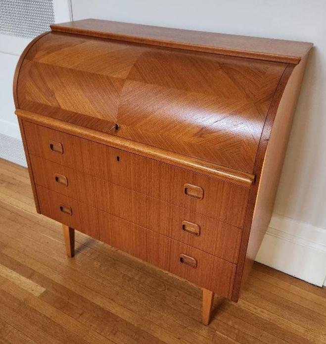 Made in Sweden, this Mid-century teak desk is perfect for your home office. When top is open, desk top slides out 9 1/2" - perfect for a laptop computer. Plenty of cubbies and drawers above for small items and 3 larger drawers below to keep you organized. Gorgeous teak woodgrain with tapered legs. Comes with one key to lock lid and top drawer. Made by Egon Ostergaard-Cook Street Vintage