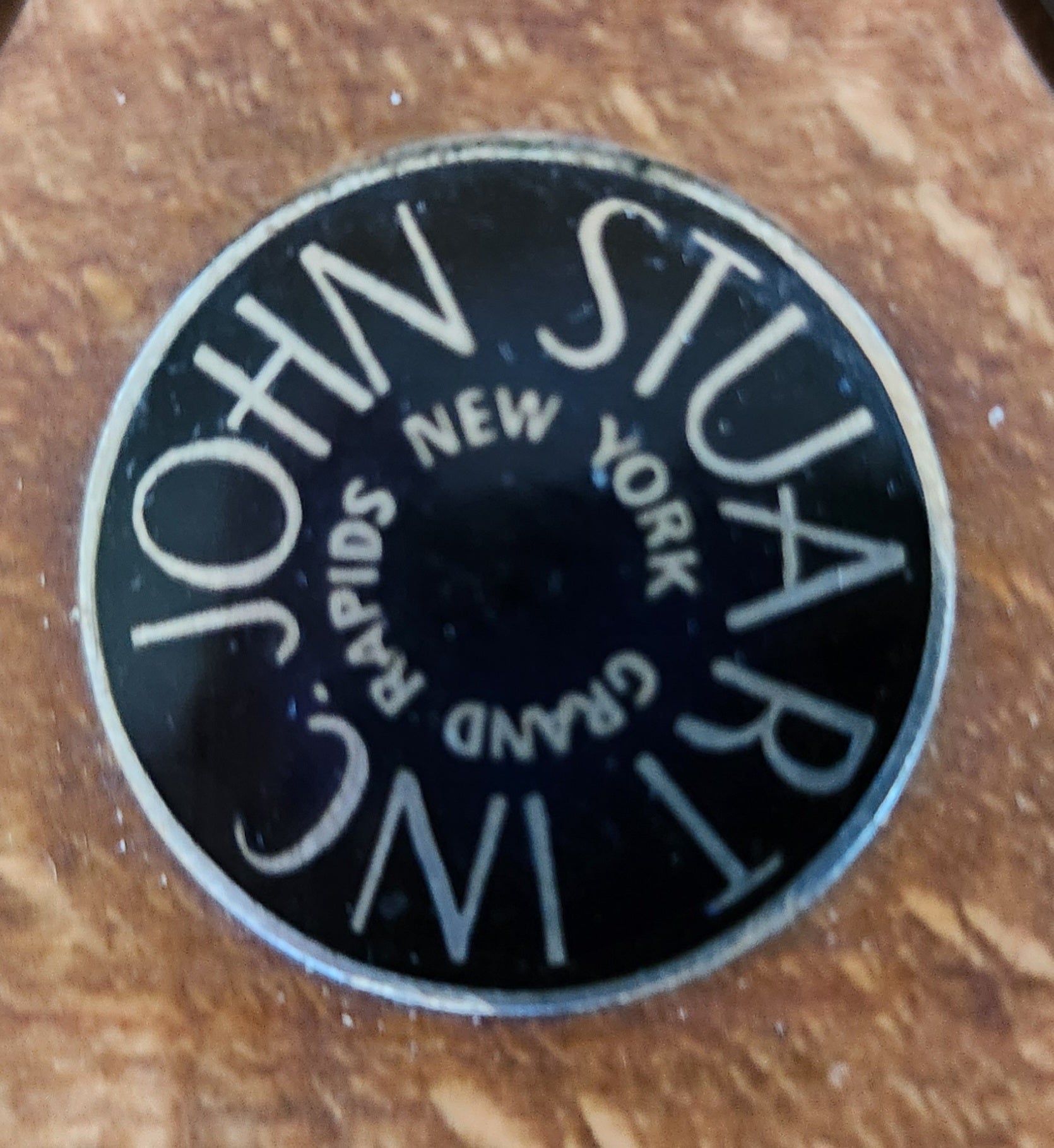 Circular logo with 'John Stuar & Co. Grand Rapids, New York' text on a wooden background
