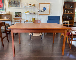 Side view of gorgeous MCM teak ining table with Iittala glassware in the background and Sid Barron artwork- Cook Street Vintage