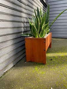 The perfect touch for any room. The original styrofoam inserts accommodate three medium-sized plants. Makeshift wood lid that can transform this unit into a small side table or storage bin. side view with plants.- Cook Street Vintage