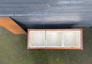 Top view showing styrofoam inserts and plants removed. The perfect touch for any room. The original styrofoam inserts accommodate three medium-sized plants. Makeshift wood lid that can transform this unit into a small side table or storage bin- Cook Street Vintage