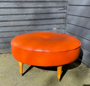 Classic round four leg round foot stool in orange. Tapered legs with brass caps. Centre button detail on cushion- Cook Street Vintage.
