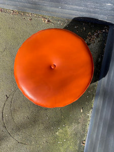 Classic MCM round four leg round ottoman top in orange. Tapered legs with brass caps. Centre button detail on cushion- Cook Street Vintage.