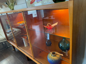 Whether to showcase your midcentury barware, vintage glassware or ceramic collection, your china or books, this gorgeous Danish designed glass front cabinet has perfect lighting to create a stunning display. Three sliding glass doors with teak trim open to adjustable height glass shelves. Subtle arch top curtain. Made in Denmark by Laurits M Larsen Mobelfabrik.- Cook Street Vintage