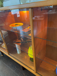 Whether to showcase your midcentury barware, vintage glassware or ceramic collection, your china or books, this gorgeous Danish designed glass front cabinet has perfect lighting to create a stunning display. Three sliding glass doors with teak trim open to adjustable height glass shelves. Subtle arch top curtain. Made in Denmark by Laurits M Larsen Mobelfabrik.- Cook Street Vintage
