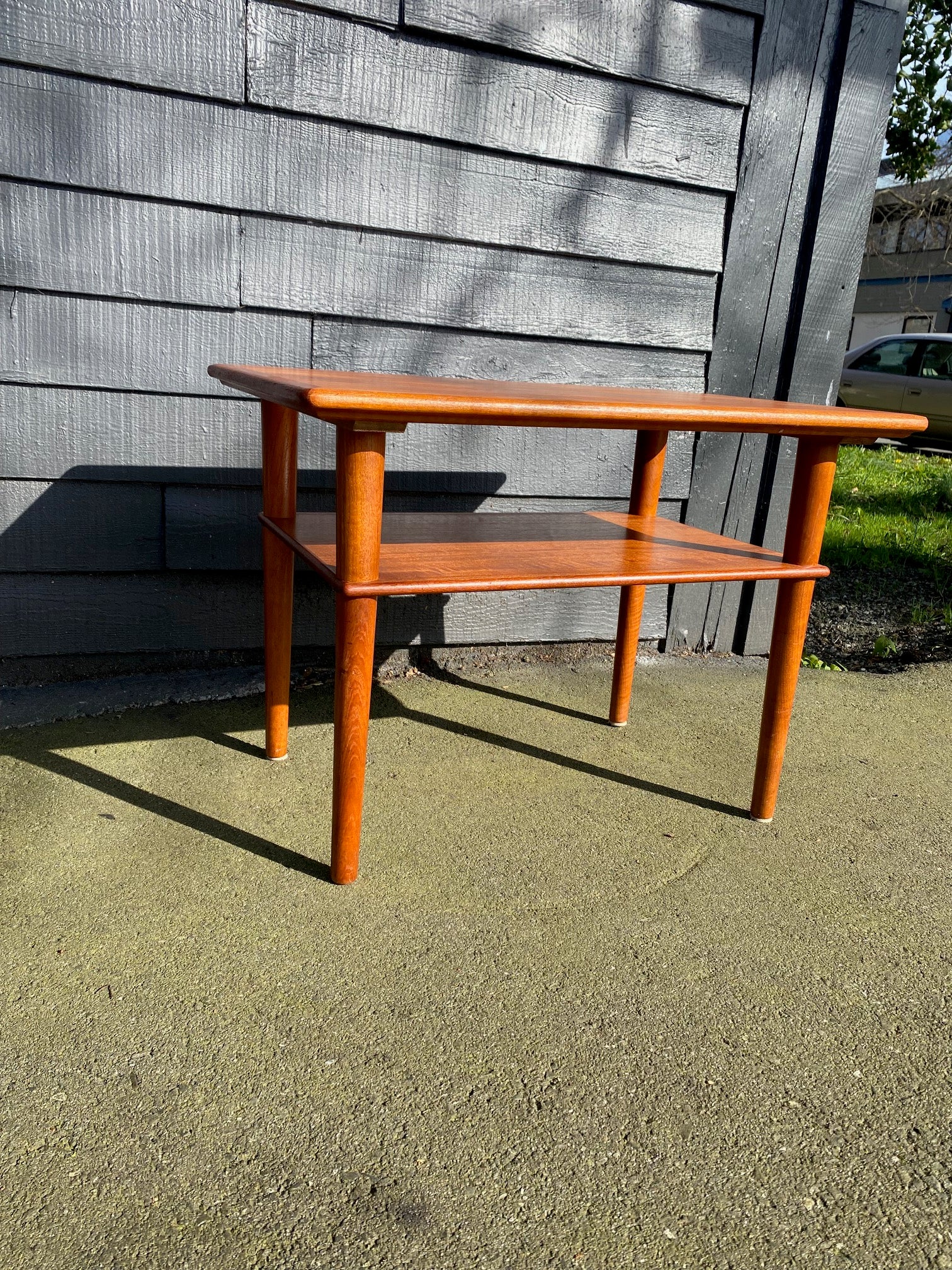 Nice mid-century Scandinavian design teak side table with lower magazine shelf. Elegant tapered legs- Cook Street Vintage
