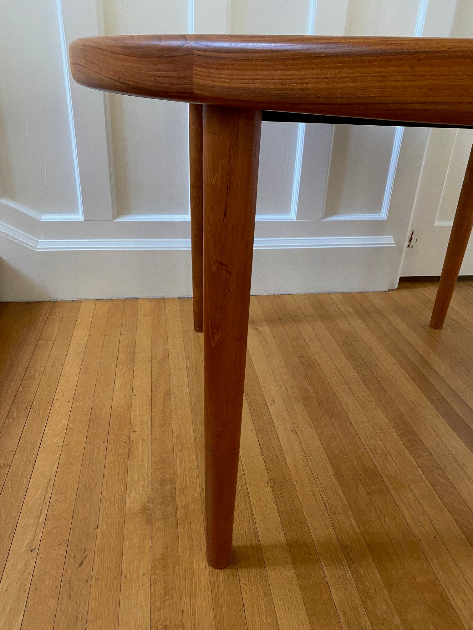 detail of leg and edge of Gorgeous Mid-century honey teak round dining table. Smaller profile than our other round dining tables, this beauty has an elegant staved edge of solid teak- Cook Street Vintage