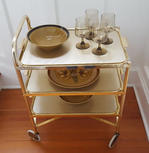 Midcentury Three Level Folding Gold Tea Trolley with dishes and glasses Cook Street Vintage