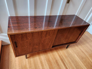 Beautiful Danish rosewood sideboard. Sliding cabinet doors with adjustable interior shelves. One felt lined hidden drawer. Made in Denmark by Poul Dogvad for Hundevad & Co- Cook Street Vintage
