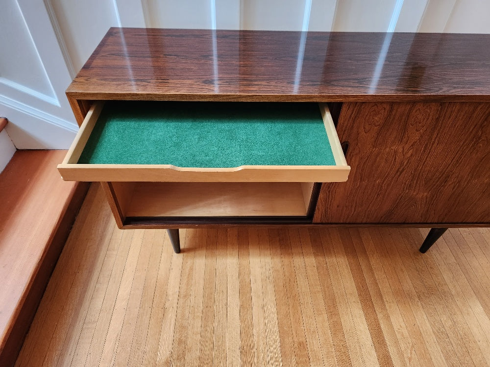 Beautiful Danish rosewood sideboard. Sliding cabinet doors with adjustable interior shelves. One felt lined hidden drawer. Made in Denmark by Poul Dogvad for Hundevad & Co- Cook Street Vintage