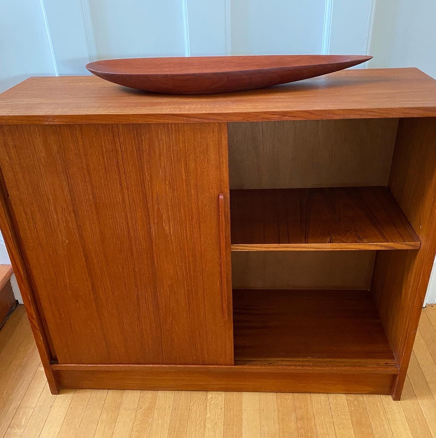 MCM teak cabinet with right sliding door open and teak tear shaped dish on top- Cook Street Vintage