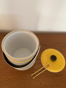 Top view of vinyl ice bucket with lid on table and yellow plastic tongs resting on lid with wood knob- Cook Street Vintage