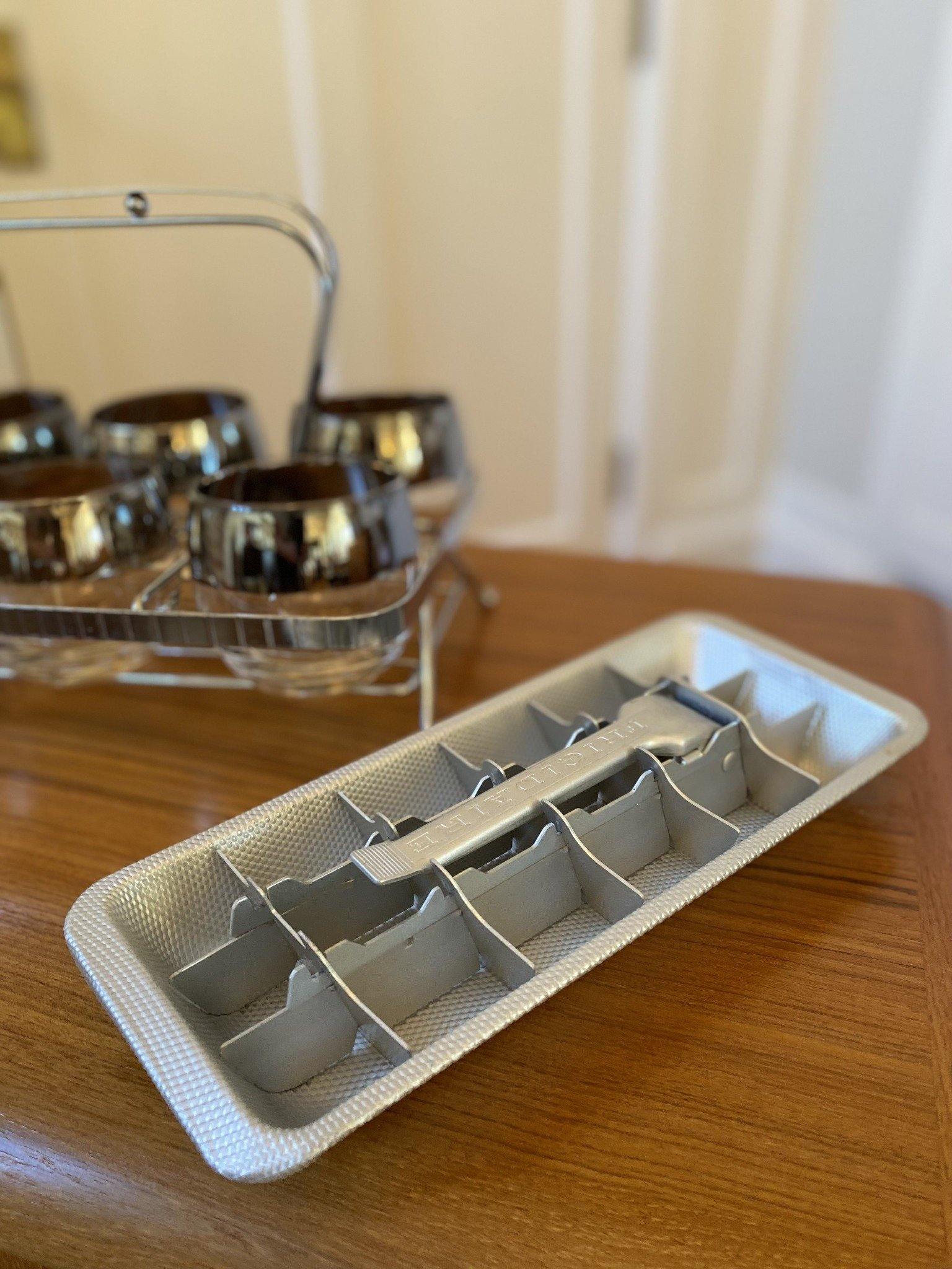 Metal Frigidaire ice cube tray with glasses in background- Cook Street Vintage