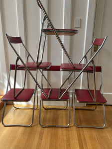 6 red vinyl and chrome fodling chairs stacked in a pyramid-Cook street Vintage