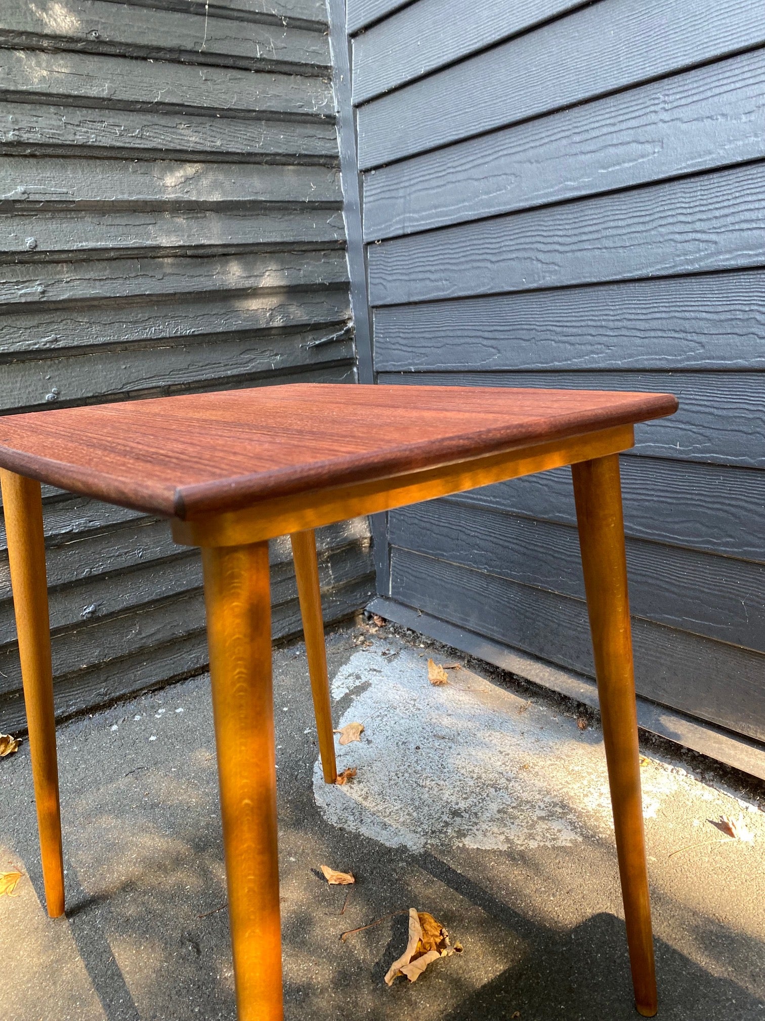 Side view of Gorgeous mid-century Scandinavian design teak side table with curved edge and elegant tapered legs- Cook Street Vintage