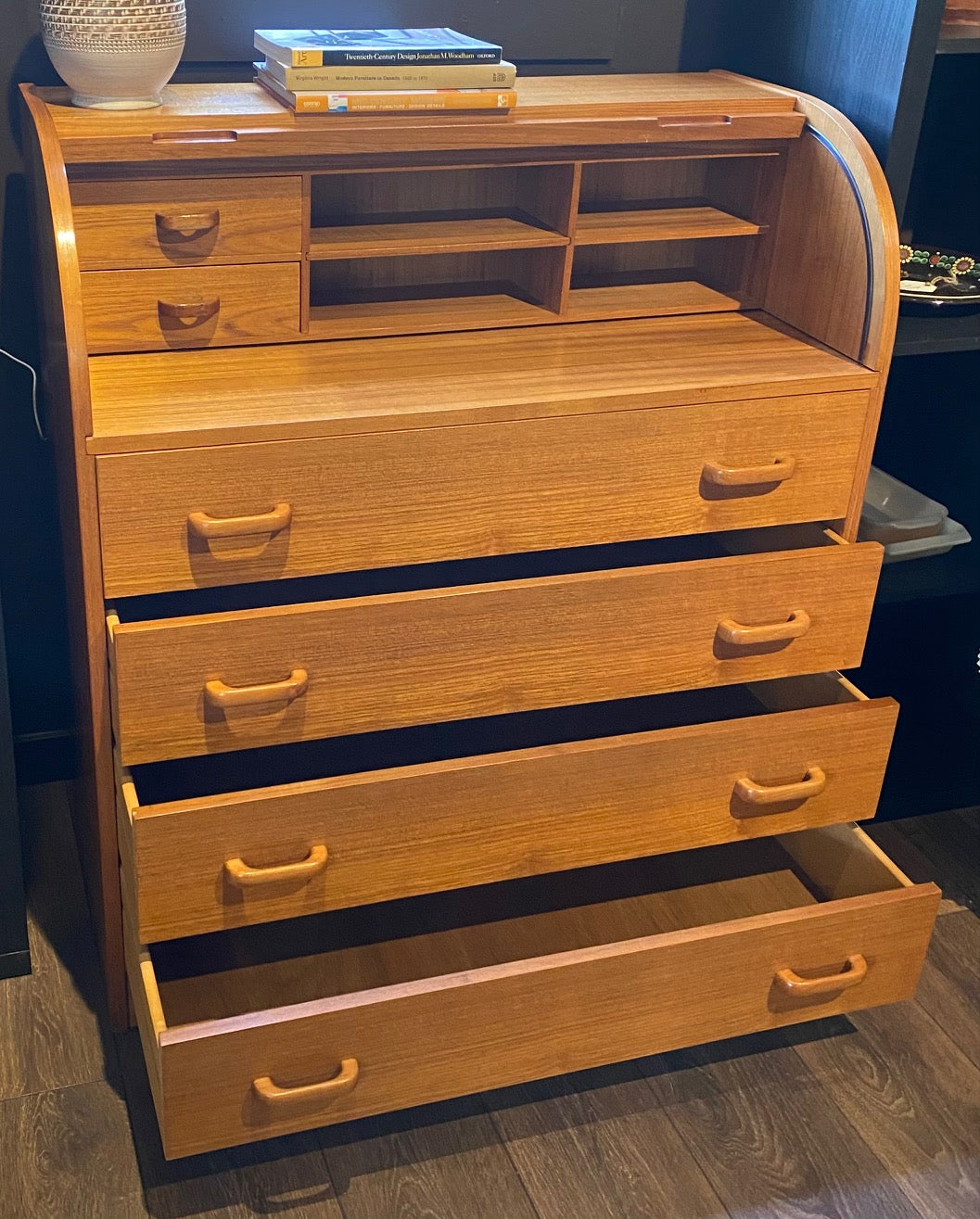 Gorgeous Scandinavian design mid-century roll-top teak desk. Top rolls up to reveal cubby holes, two small drawers and a removable shelf. Top is a retractable desktop. Lower cabinet includes four large drawers- Cook Street Vintage