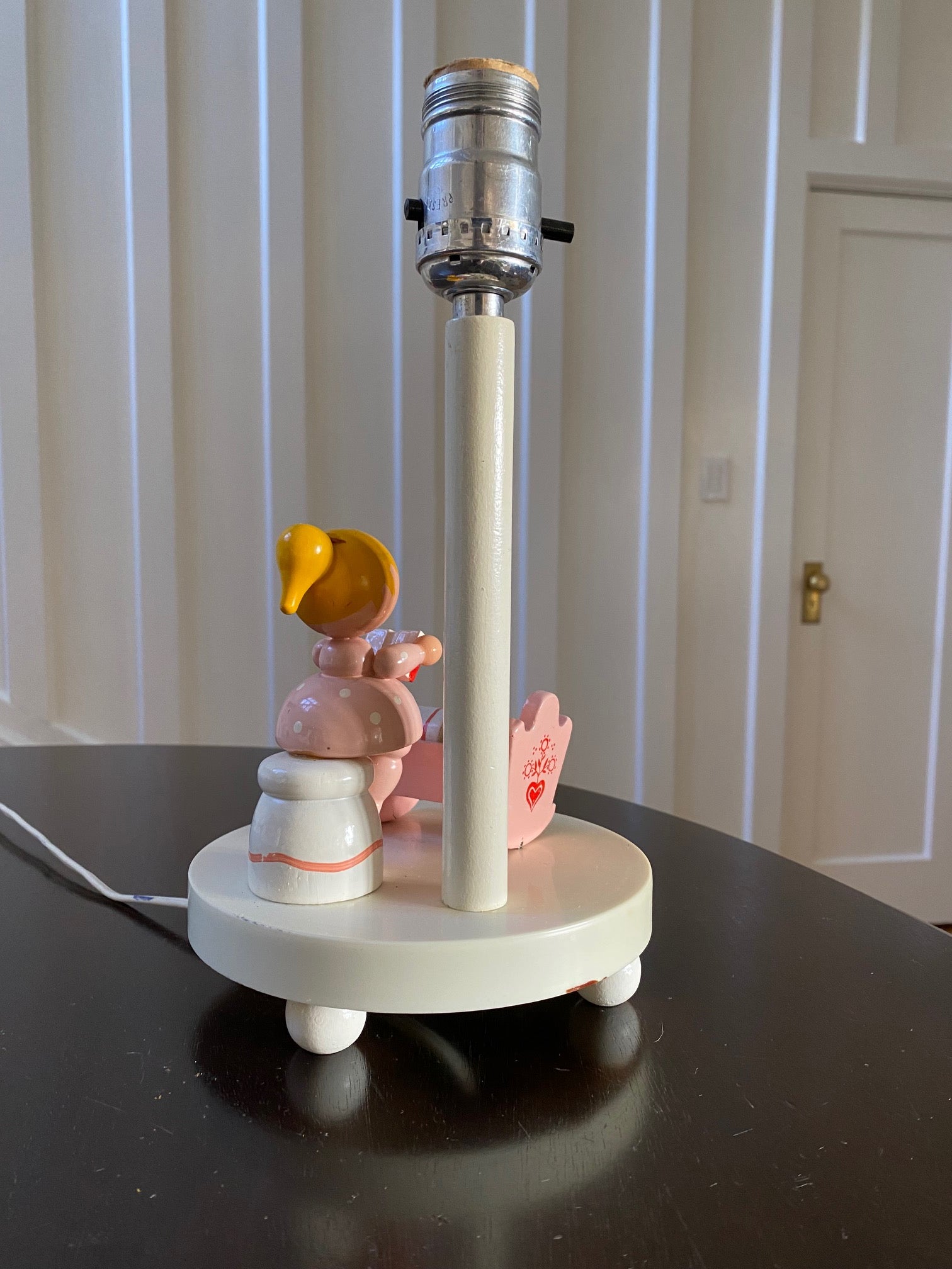 Back view of white nursery lamp with figure of mother reading to baby in pink cradle- Cook Street Vintage