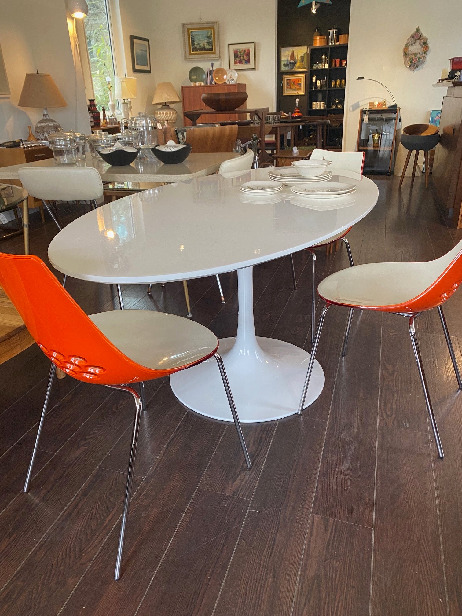 Stunning white laminate tulip table. Gorgeous beveled edge and metal base. In nice overall condition with some scratching on table surface. Shown with orange Calligaris "Jam" dining chairs- Cook Street Vintage