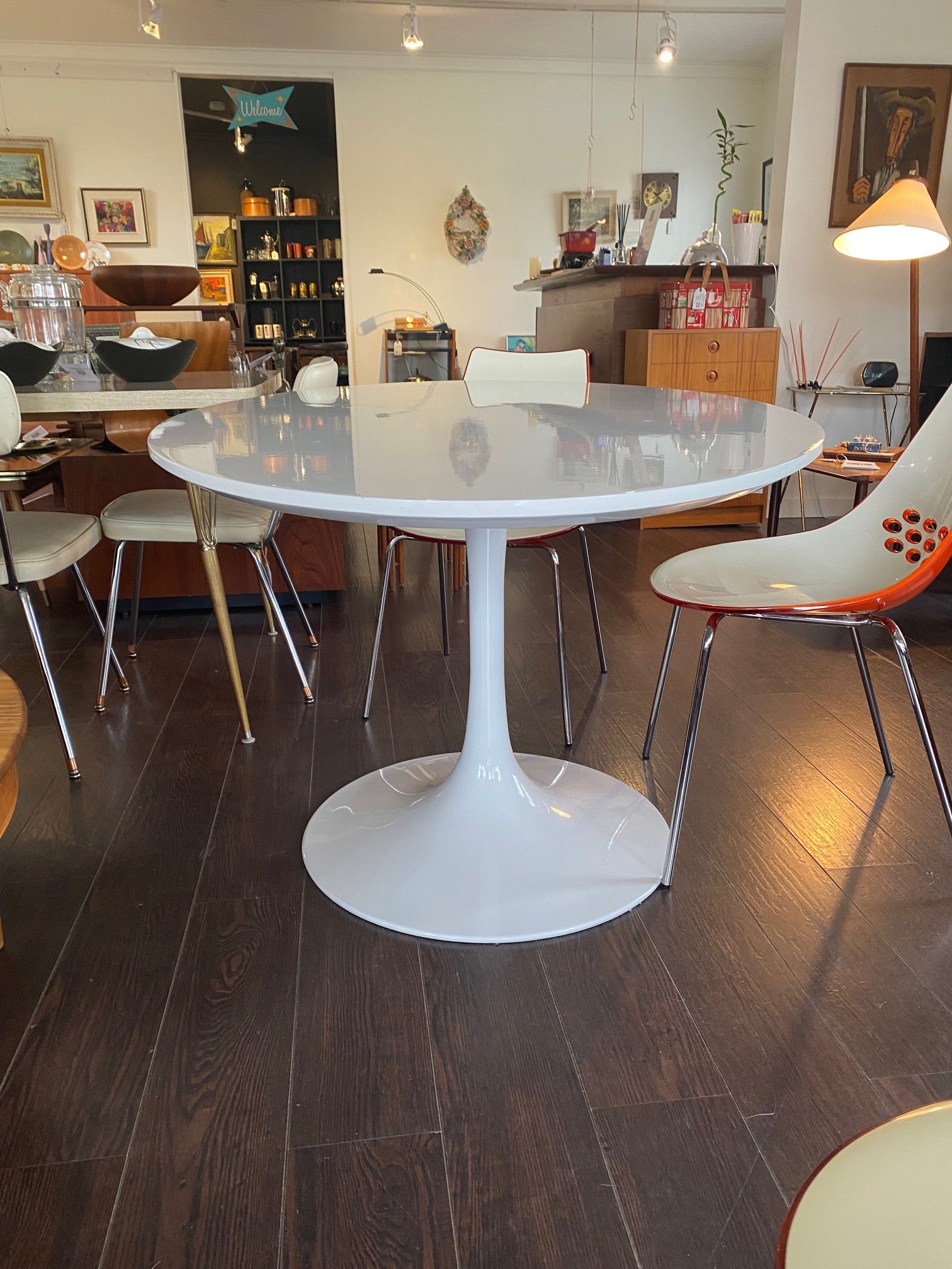 Stunning white laminate tulip table. Gorgeous beveled edge and metal base. In nice overall condition with some scratching on table surface. Shown with orange Calligaris "Jam" dining chairs- Cook Street Vintage