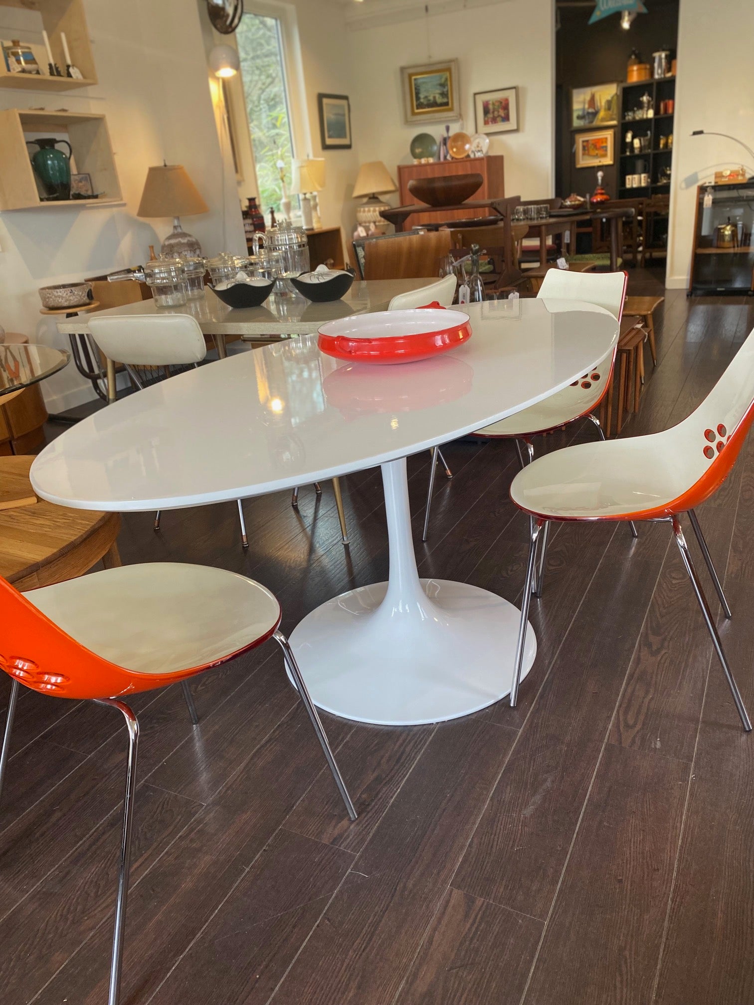 Stunning white laminate tulip table. Gorgeous beveled edge and metal base. In nice overall condition with some scratching on table surface. Shown with orange Calligaris "Jam" dining chairs- Cook Street Vintage
