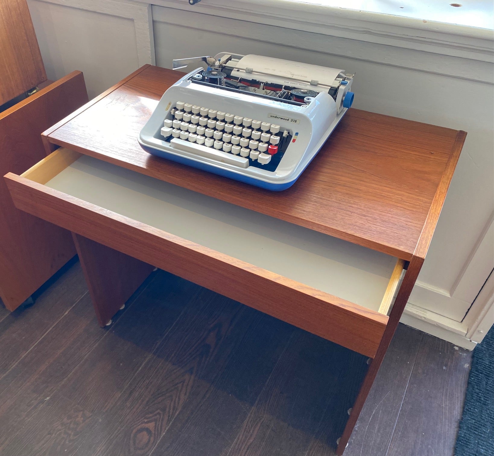 Small teak desk with handy drawer open. Shown with a portable Underwood typewriter- Cook Street Vintage
