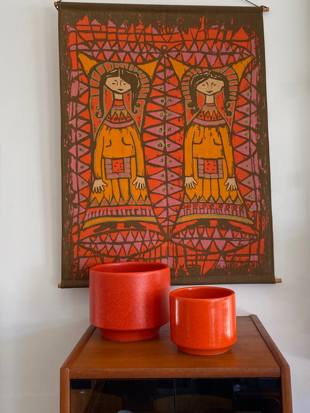 Colourful Mid-century linen wall hanging in orange, red, pinkand brown shown with two ornage Gainey ceramic planters- Cook Street Vintage